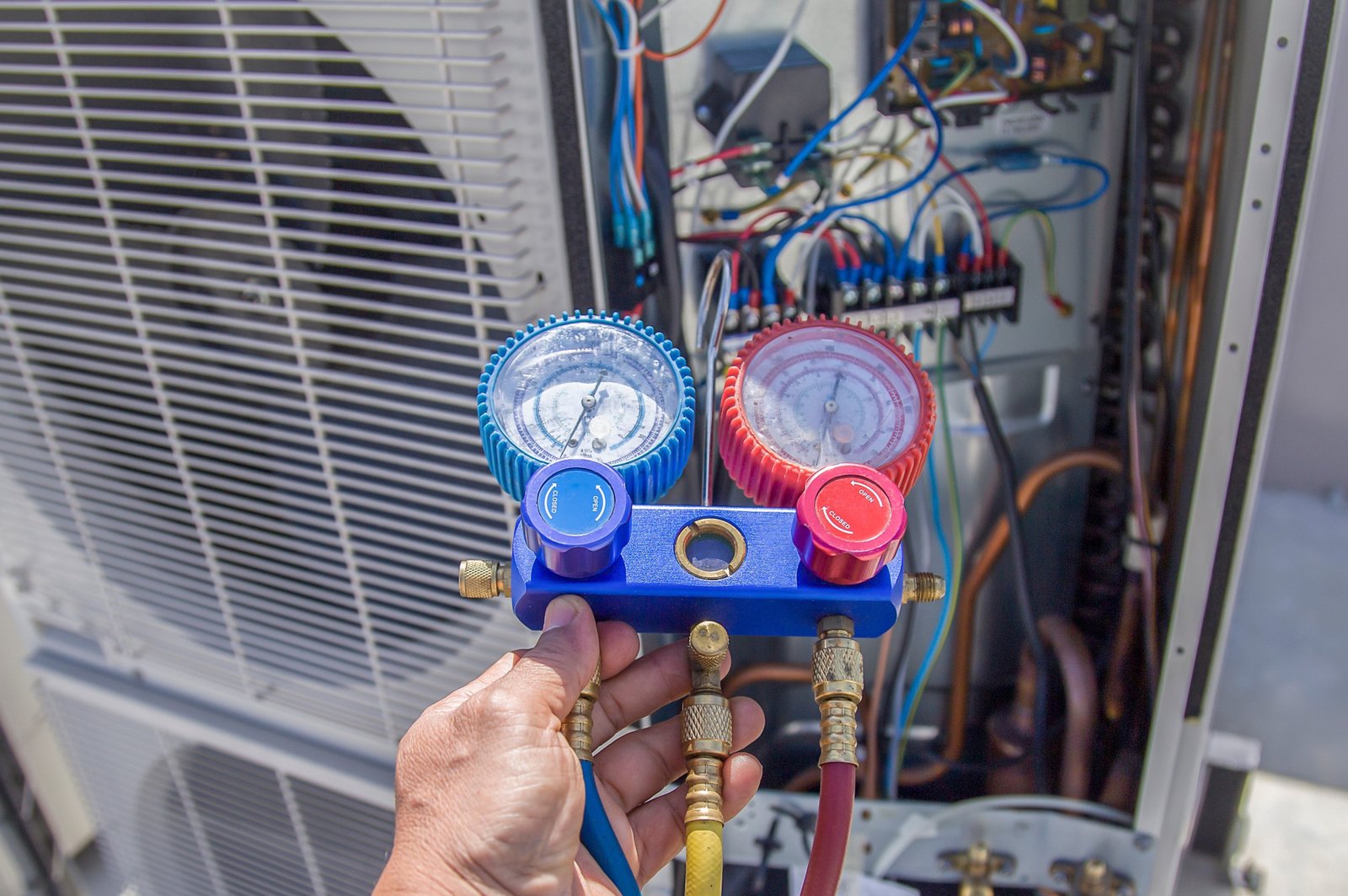 An Air Dynamics of Tulsa HVAC technician using a manifold gauge to perform an AC repair diagnostics check in Tulsa, OK.